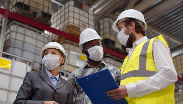 Health and safety audit: Safety inspection in an industrial setting with employees wearing protective gear.