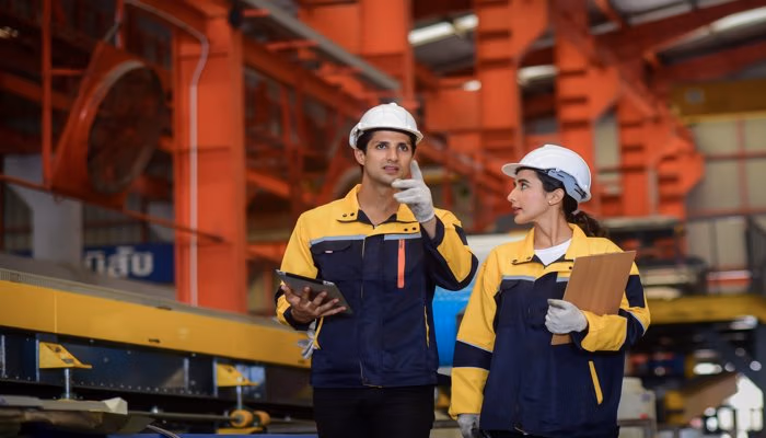 Operator round in an industrial setting, with two workers discussing and inspecting equipment.